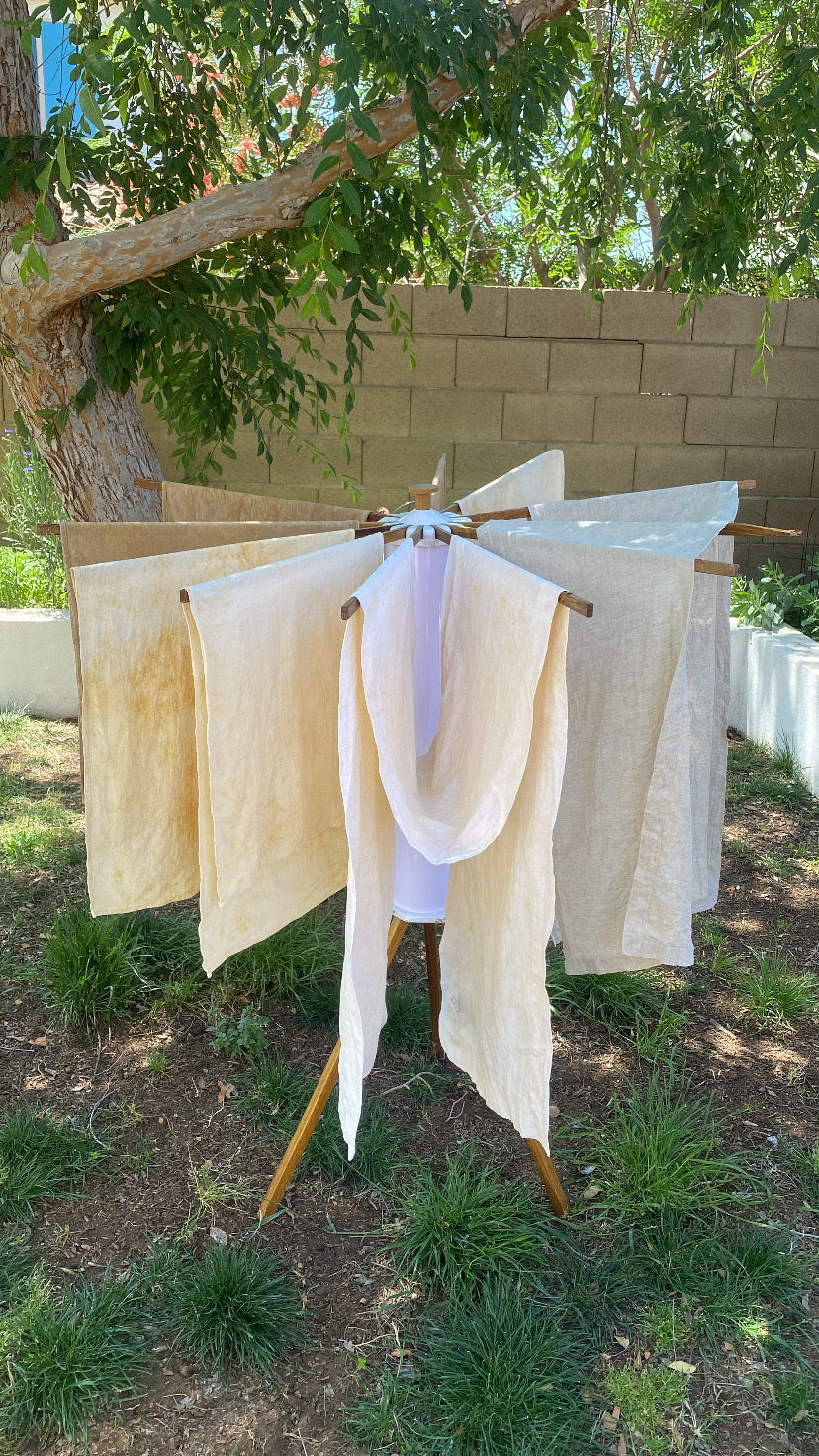 Clothesline with white and beige fabric hanging outdoors under a tree