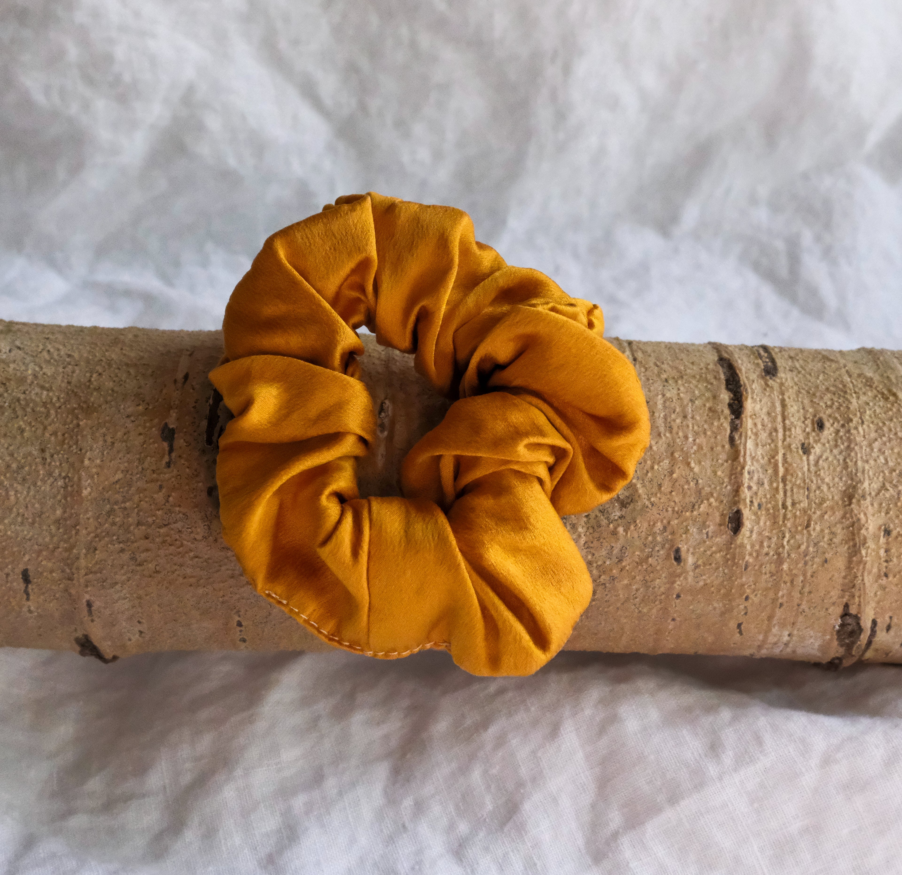 pumpkin scrunchie on a wooden stick with a white fabric background