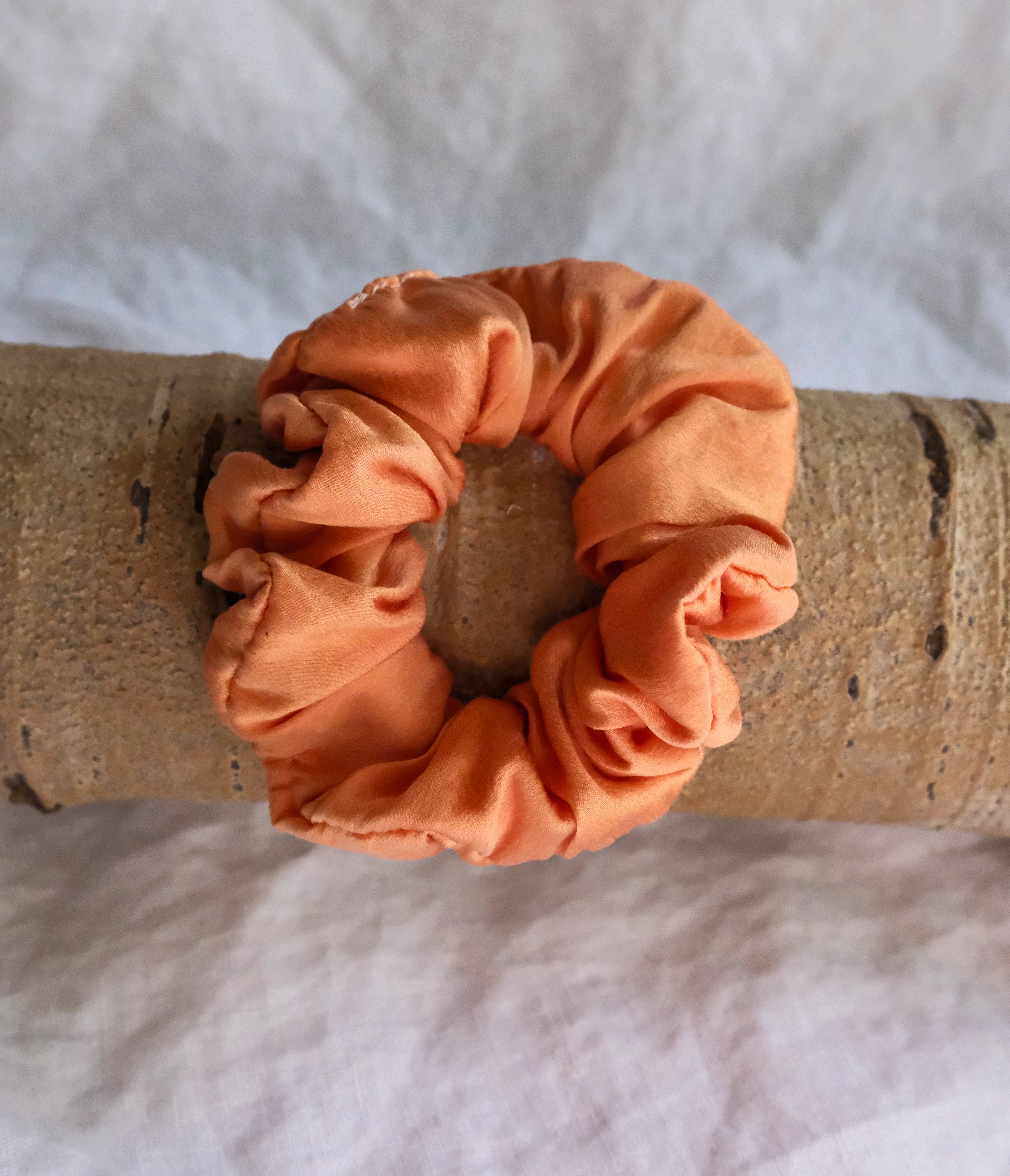 Salmon scrunchie on a wooden block with a white background