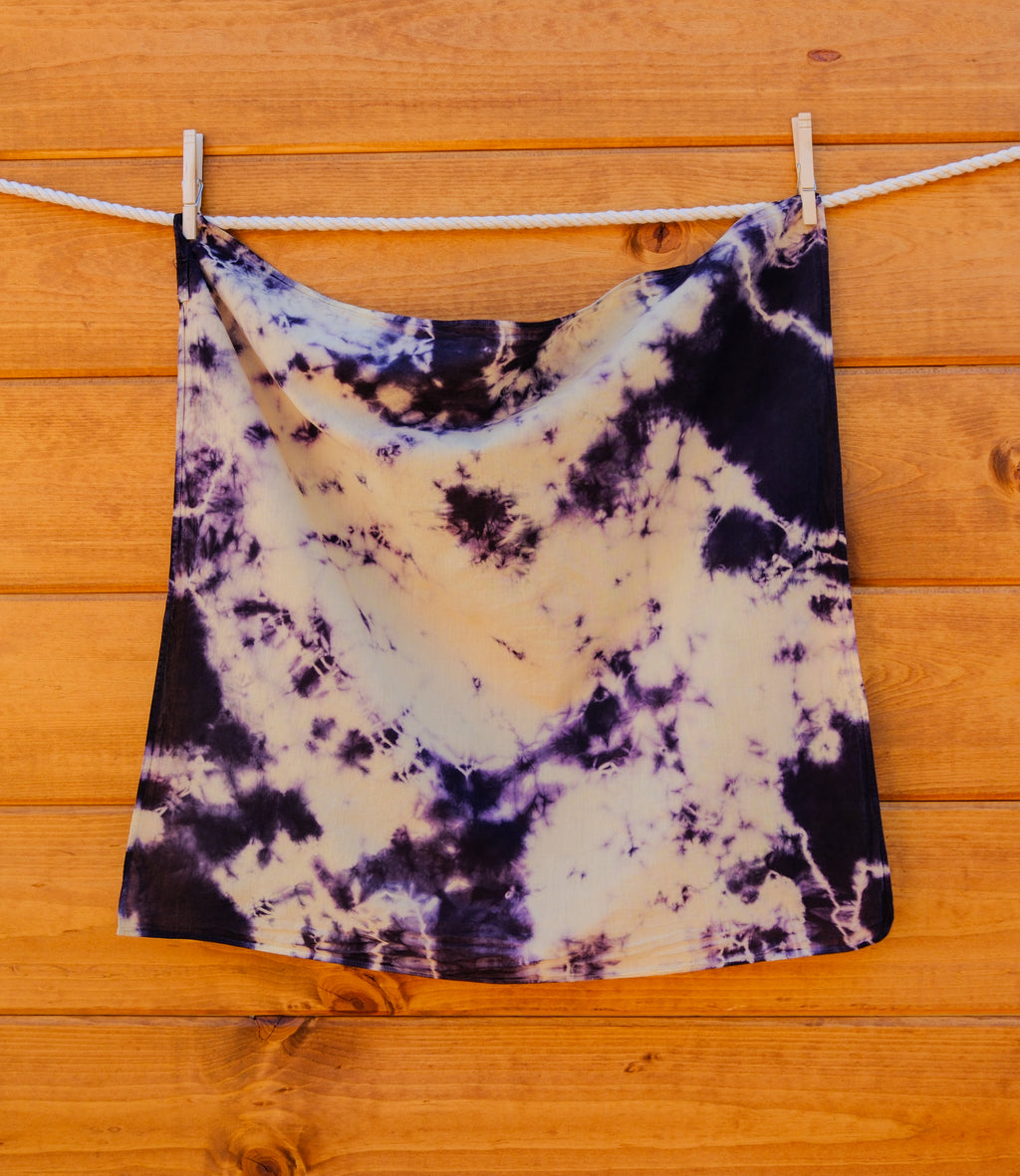 Tie-dye bandana hanging on a clothesline against a wooden background