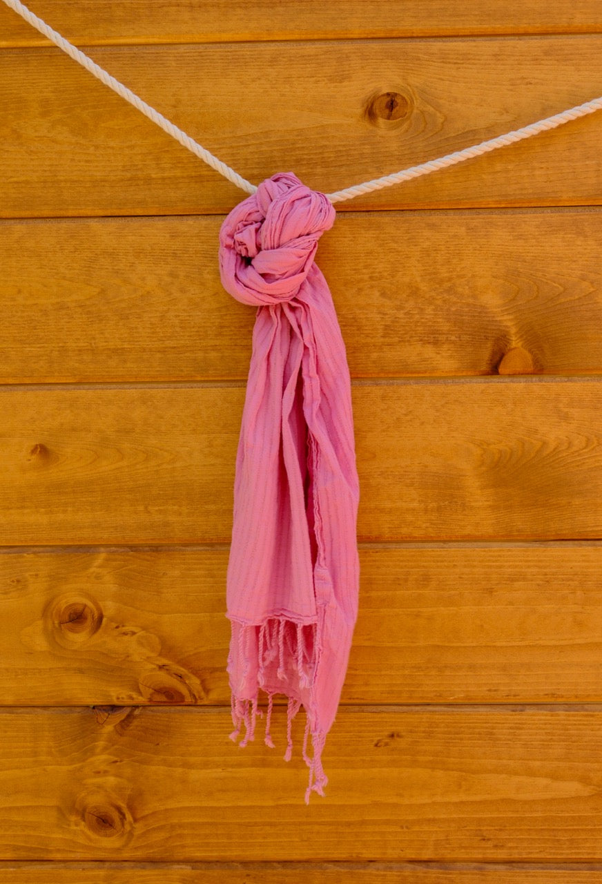 Pink scarf tied into a knot on a wooden surface