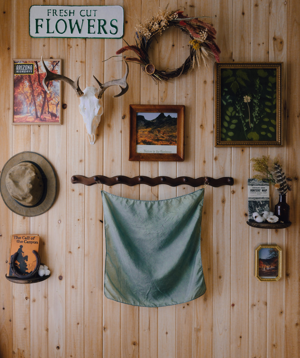 Wooden wall with decorative items including a deer skull, wreath, and framed pictures.