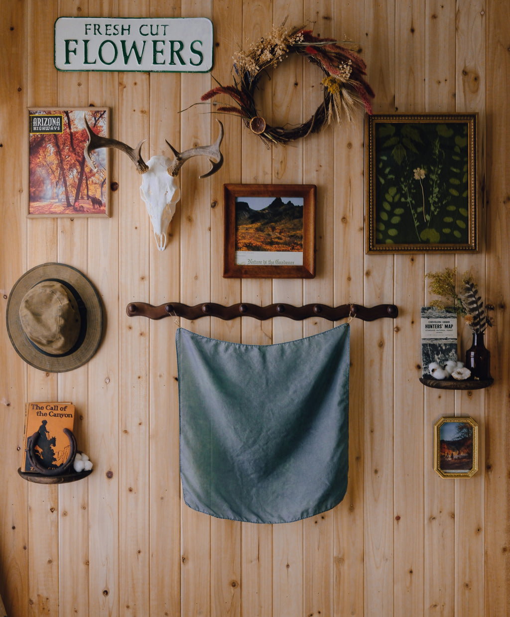 Wooden wall with decorative items including a deer skull, wreath, and framed pictures.