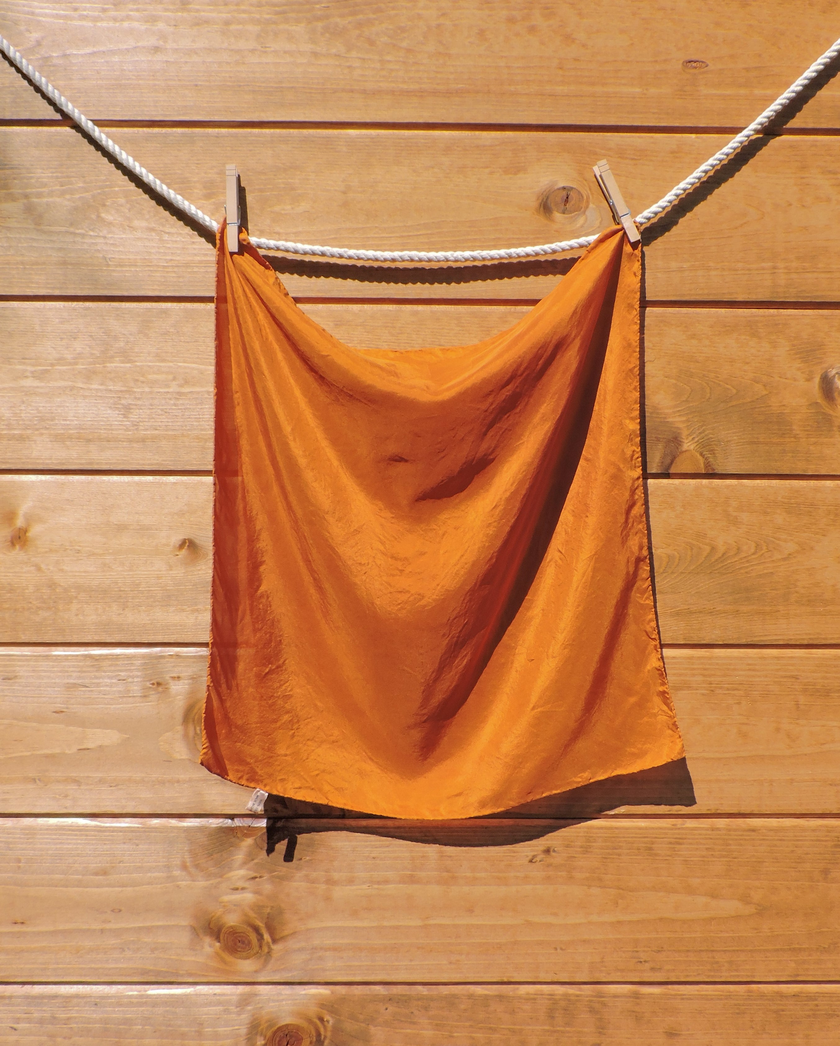 Dark orange scarf hanging on a wooden wall