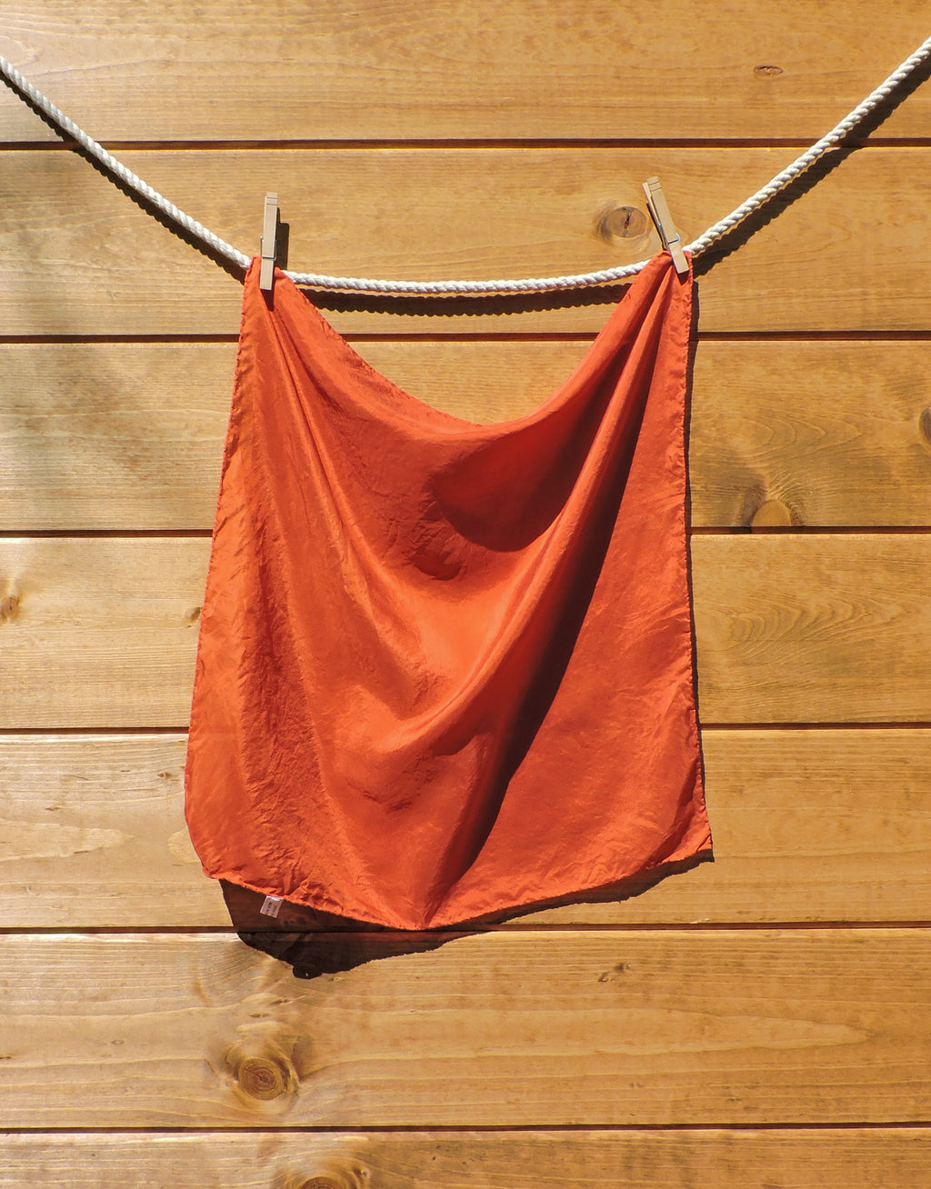 red scarf hanging on a wooden wall