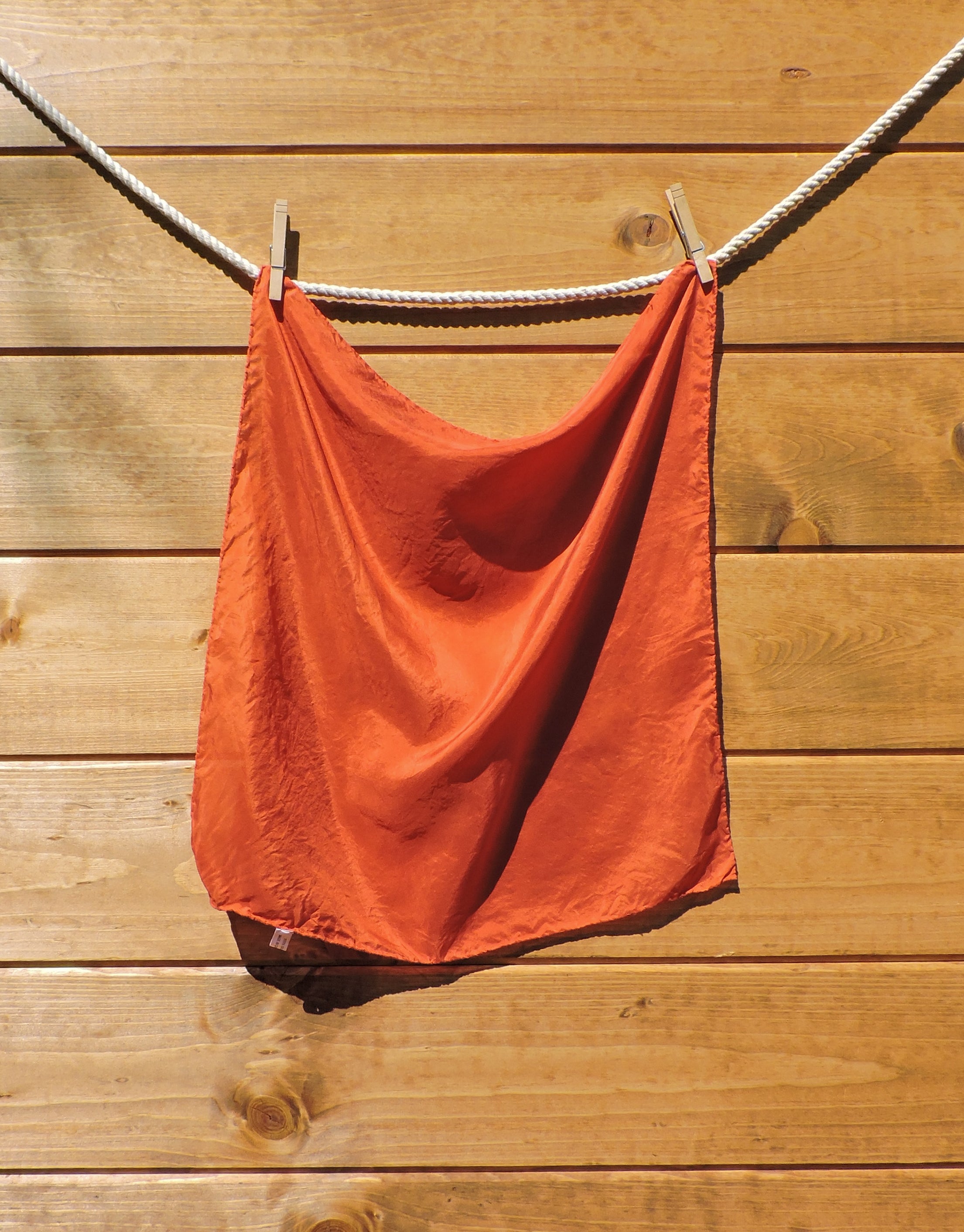 red scarf hanging on a wooden wall