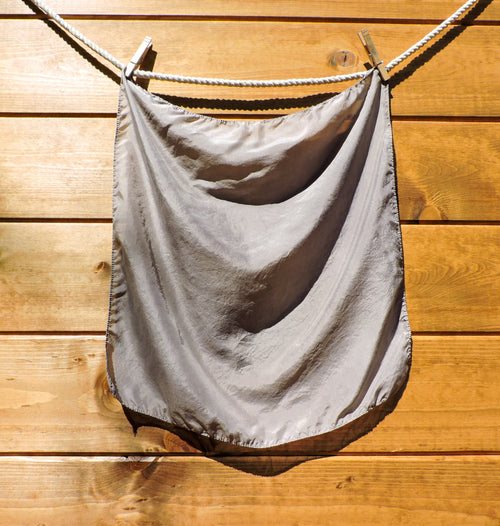 silk scarf hanging on a clothesline against a wooden wall