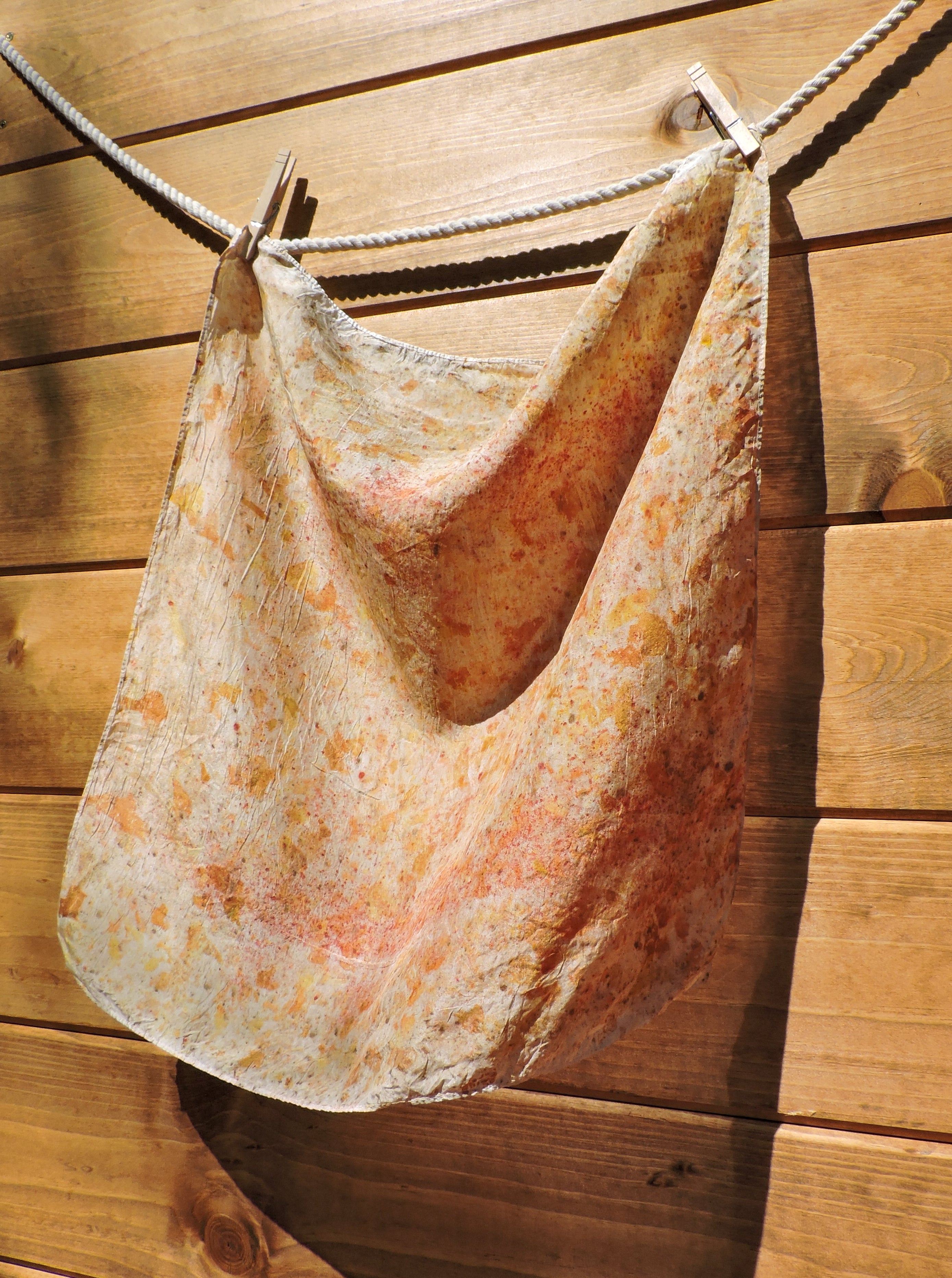 Silk scarf with floral pattern hanging on a wooden wall