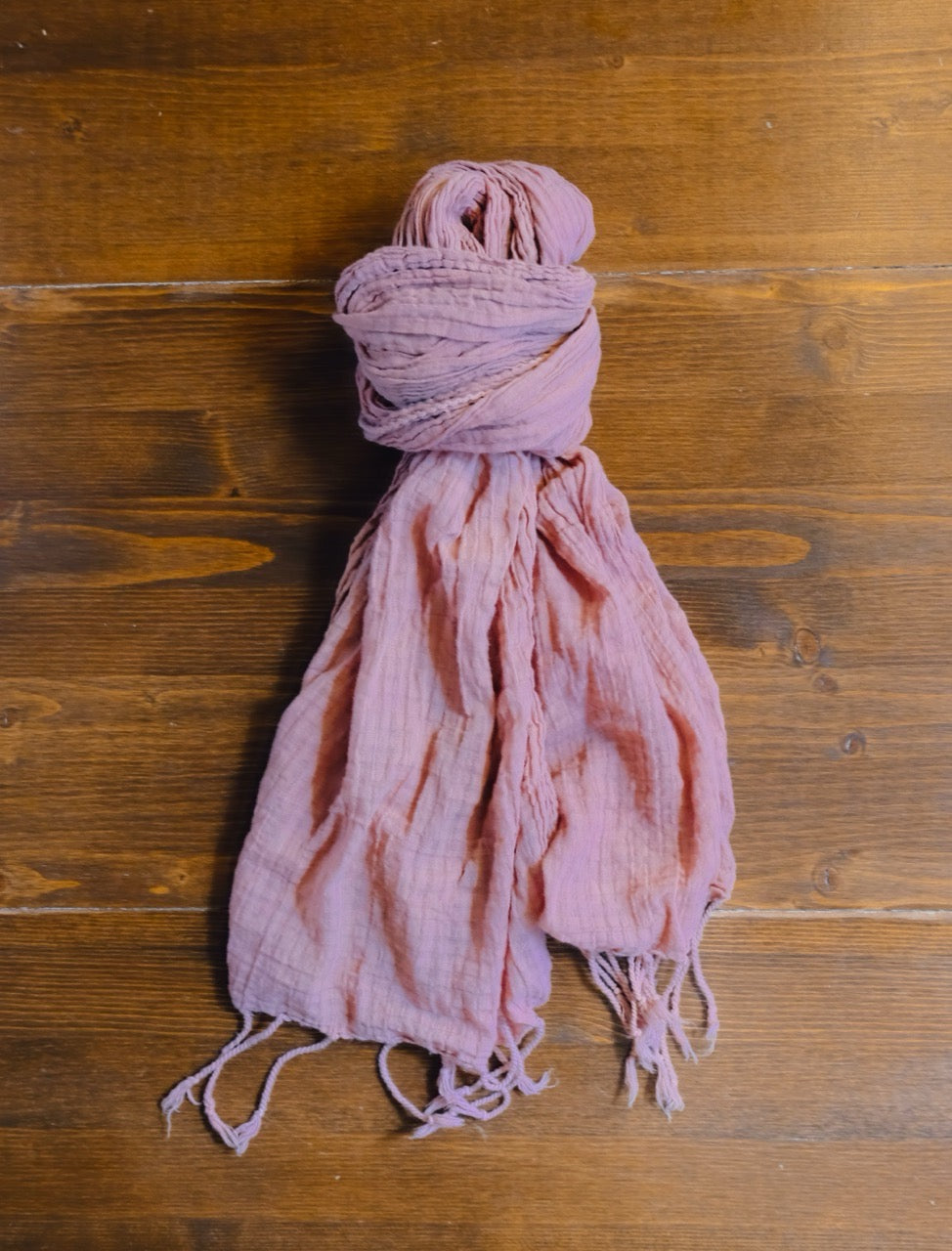 brick colored scarf with tassels on a wooden surface