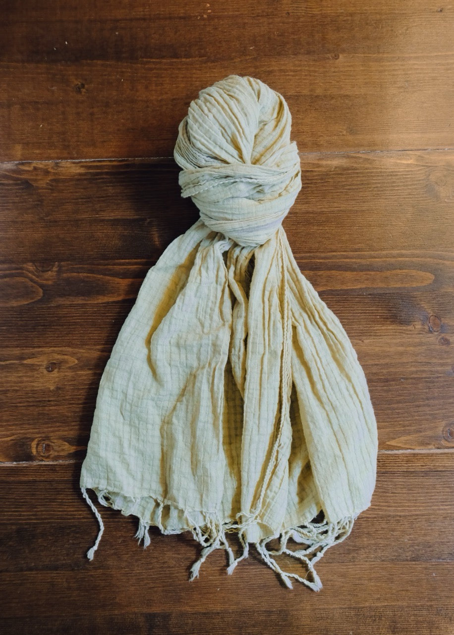 green scarf with tassels on a wooden surface