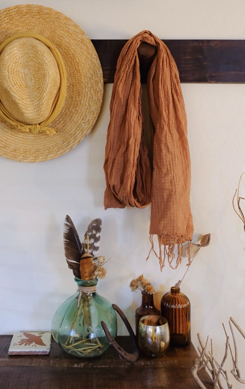 Decorative setup with a straw hat, scarf, and various items on a wooden surface against a white wall.