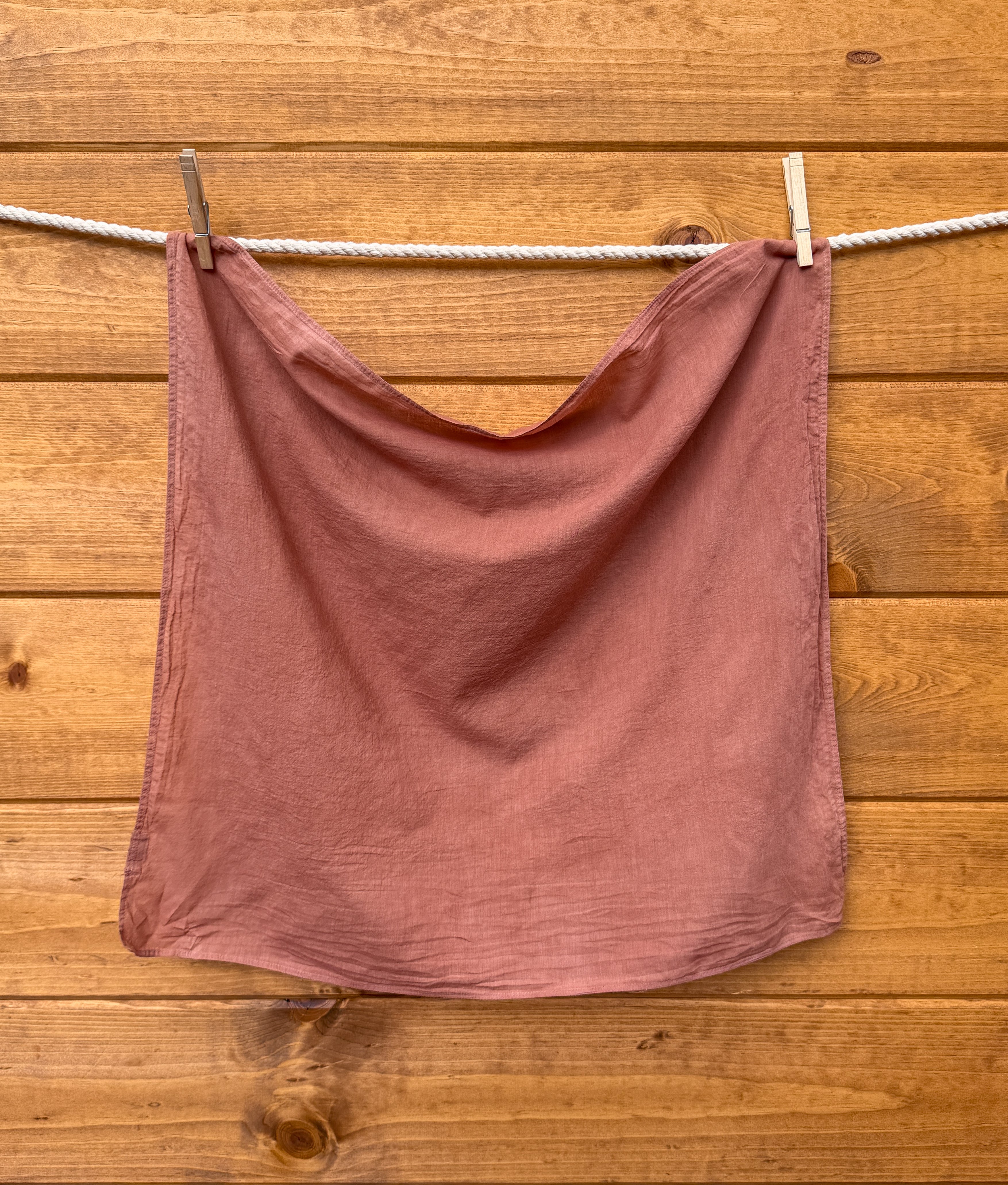 brick colored bandana on a clothesline against a wooden wall