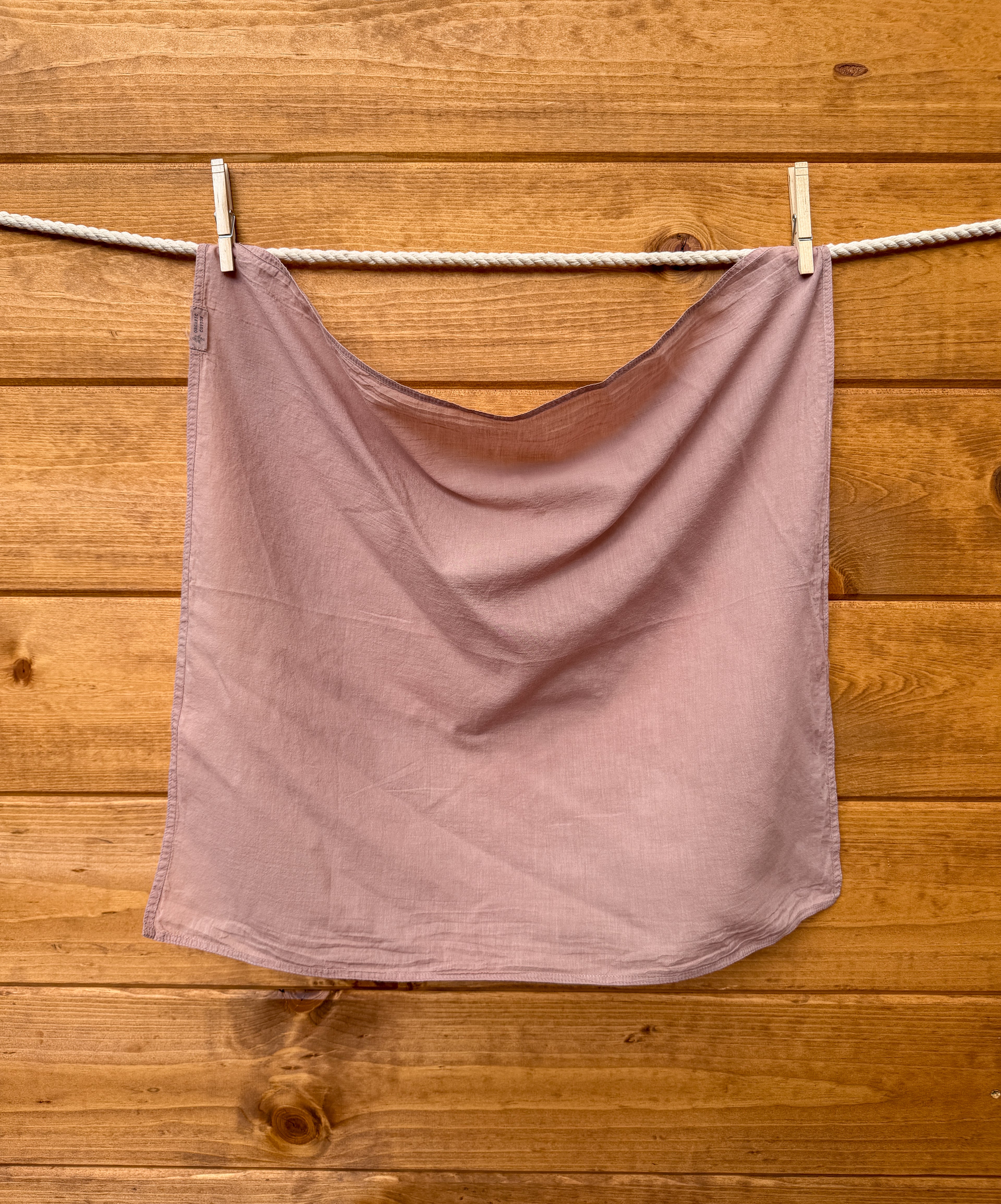 light sienna bandana hanging on a clothesline against a wooden wall