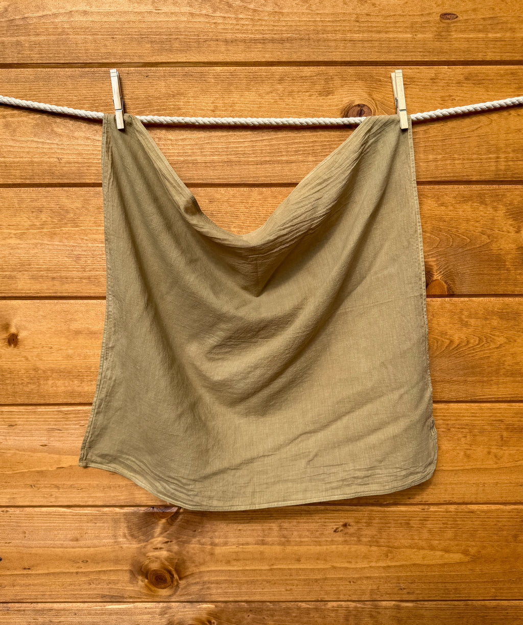 olive green bandana hanging on a clothesline against a wooden wall