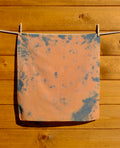 Tie-dye bandana hanging on a clothesline against a wooden wall
